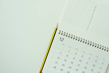 Beyaz masa arkaplanındaki takvim ve kalemi kapat, iş toplantısı ya da seyahat planlama konsepti için planlama