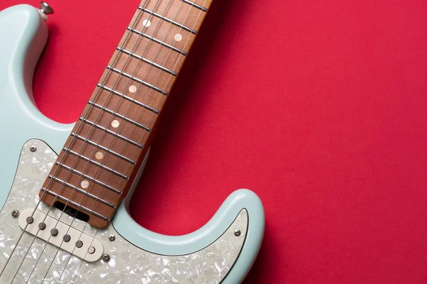 Electric guitar on red table background, close up music concept
