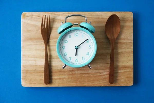 Food clock spoon and fork, Healthy food breakfast concept on blue table background