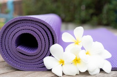 Mor yoga minderi ve açık hava çiçeği, sağlıklı ve spor konsepti.