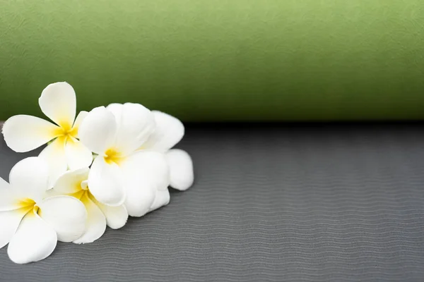 green yoga mat and a flower outdoor, healthy and sport concept