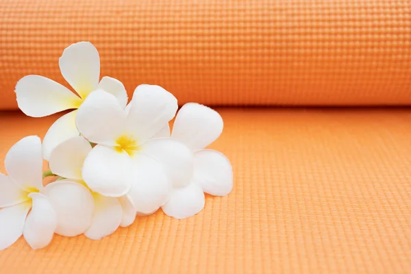 orange yoga mat and a flower outdoor, healthy and sport concept