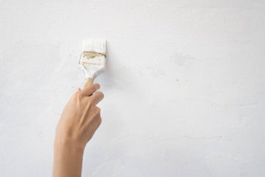 El işçisinin elinde fırçayla duvarları beyaza boyaması, boya ve onarım konsepti
