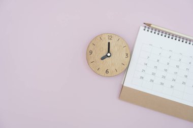 close up of calendar and alarm clock on the pink pastle table background, planning for business meeting or travel planning concept