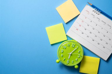 Takvimi ve saati mavi masa arkaplanına kapat, iş toplantısı ya da seyahat planlama konseptini planla