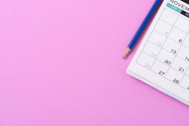 Pembe masa arkaplanındaki takvim ve kalemi kapat, iş toplantısı ya da seyahat planlama konseptini planla