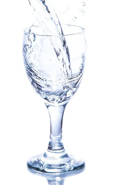 Água derramando em um copo no fundo branco . — Fotografia de Stock