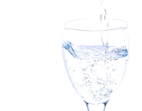 Água derramando em um copo no fundo branco . — Fotografia de Stock