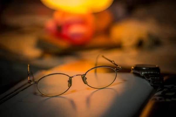 Vintage still life with old spectacles on book near desk lamp