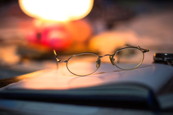 Vintage still life with old spectacles on book near desk lamp — Stock Photo, Image