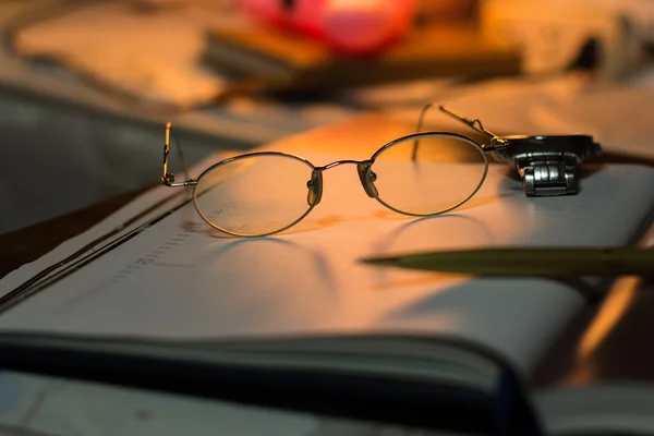 Vintage still life with old spectacles on book near desk lamp — Stock Photo, Image