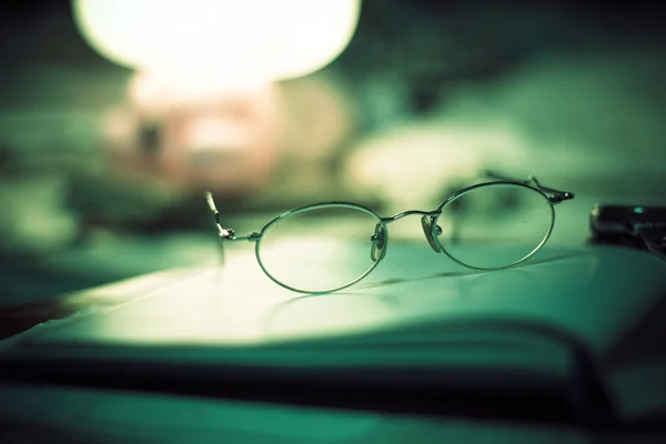 Vintage Stilleven met oude bril op boek in de buurt van bureaulamp Stockafbeelding
