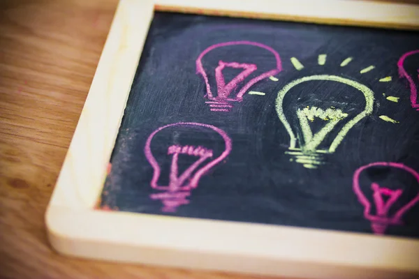 Funny lightbulb on blackboard, concept of uniqueness — Stock Photo, Image