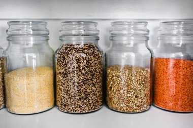 Değişik tahıl türleri ve sağlıklı malzemelerle dolu temiz kiler kavanozları. İçinde kinoa karabuğday polenta ve arpa da var. Basit malzeme kavramı.