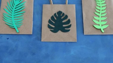 Çevresel farkındalık ve tüketici davranışı kavramsal imaj, üzerinde tropikal yeşil kağıt yapraklar olan sürdürülebilir kağıt alışveriş torbası