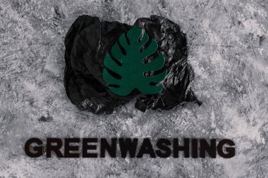 yeşil çamaşır ve sürdürülebilir kavramsal görüntü gibi davranan şirketler, altında yazı olan atık parçalarının yanında kağıt yaprak