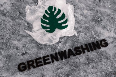 yeşil çamaşır ve sürdürülebilir kavramsal görüntü gibi davranan şirketler, altında yazı olan plastik atıkların yanında kağıt yaprak