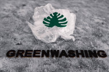 yeşil çamaşır ve sürdürülebilir kavramsal görüntü gibi davranan şirketler, altında yazı olan plastik atıkların yanında kağıt yaprak