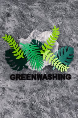 yeşil yıkama ve sürdürülebilir kavramsal imaj gibi davranan şirketler, kağıt yaprakları altında yazı olan plastik atıkları örtüyor.