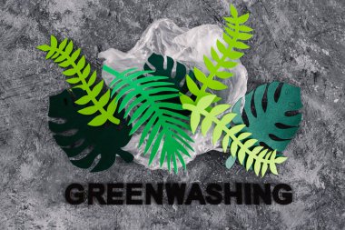 yeşil yıkama ve sürdürülebilir kavramsal imaj gibi davranan şirketler, kağıt yaprakları altında yazı olan plastik atıkları örtüyor.