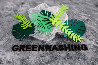 yeşil yıkama ve sürdürülebilir kavramsal imaj gibi davranan şirketler, kağıt yaprakları altında yazı olan plastik atıkları örtüyor.