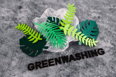 yeşil yıkama ve sürdürülebilir kavramsal imaj gibi davranan şirketler, kağıt yaprakları altında yazı olan plastik atıkları örtüyor.