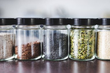 Çekirdekler, mutfak tezgahında eşleşen baharat kavanozlarında kabak chiam ve keten, basit vejetaryen malzemeler ve yemeğinizi tatlandırma konsepti.