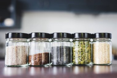 Çekirdekler, mutfak tezgahında eşleşen baharat kavanozlarında kabak chiam ve keten, basit vejetaryen malzemeler ve yemeğinizi tatlandırma konsepti.