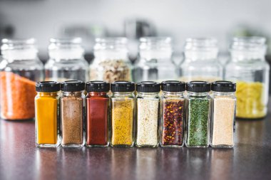 Mutfak tezgahında eşleşen baharat kavanozlarında baharat ve tahıllar, basit vejetaryen malzemeleri ve yemeğinizin lezzet konsepti.