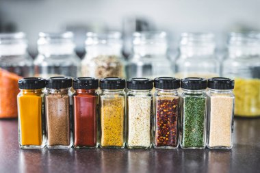 Mutfak tezgahında eşleşen baharat kavanozlarında baharat ve tahıllar, basit vejetaryen malzemeleri ve yemeğinizin lezzet konsepti.