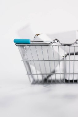 Alışveriş ve araba konseptine ekleme, alışveriş sepetinin içinde yığılmış farklı şekiller hafif mermer arka plan çekimi sığ alan derinliği