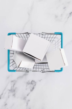 Alışveriş ve araba konseptine ekleme, alışveriş sepetinin içinde yığılmış farklı şekiller hafif mermer arka plan çekimi sığ alan derinliği