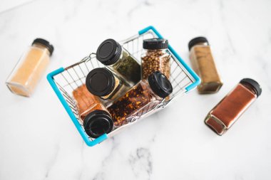 Market sepetindeki baharat kavanozlarındaki baharatlar ve baharatlar, basit vejetaryen malzemelerinin konsepti ve yemeklerinizin lezzeti.