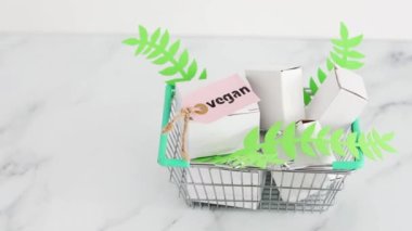 sürdürülebilirlik ve zulüm içermeyen ürün konsepti, boş ürün paketleriyle alışveriş septi ve üzerinde Vegan etiketi olan yeşil yapraklar.