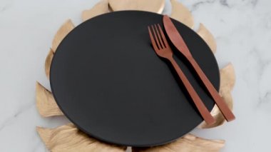 Siyah yemek tabağının üstünde altın yaprak süslemesi mermer masa, sağlıklı beslenme konsepti ve etik seçimler.