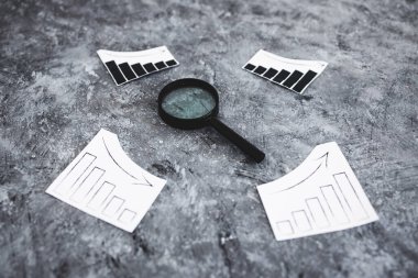 finansal piyasalar veya para ve yatırımlar kavramsal imaj, grafikler yukarı ve aşağı eğilimleri gösteren büyüteç