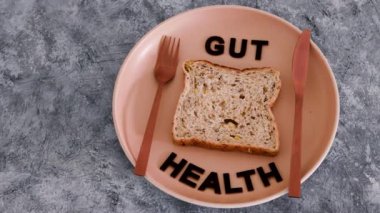 Mide sağlığı metni, kepekli çoklu çekirdekli ekmek dilimi, çatal ve bıçaklı yemek tabağı, sağlıklı beslenme ve mikrobiyom hakkında bilimsel araştırma.