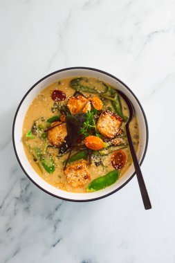 Tavada kızartılmış ipek tofu ve taze toplanmış sebze ve sağlıklı bitki temelli yemek tarifleriyle vegan Thai yeşil köri.