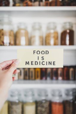 Yiyecek, raflara dizilmiş kavanozlar, sağlıklı beslenme ve sezgisel yemek kavramları olan düzenli organize edilmiş kilerin önündeki tıp metnidir.