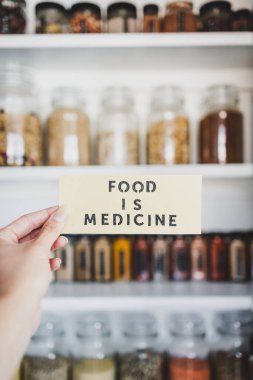 Yiyecek, raflara dizilmiş kavanozlar, sağlıklı beslenme ve sezgisel yemek kavramları olan düzenli organize edilmiş kilerin önündeki tıp metnidir.