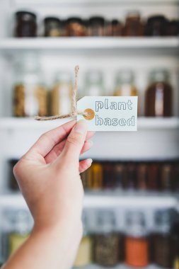 Raflara dizilmiş kavanozlar, sağlıklı beslenme ve sezgisel yeme karşı diyet kavramı ile düzenli organize edilmiş kilerin önünde bitkisel temelli metin