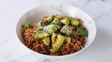 Avokado ve kızarmış soğanlı vejetaryen sarımsak ve zencefilli erişte, sağlıklı bitki temelli yemek tarifleri.