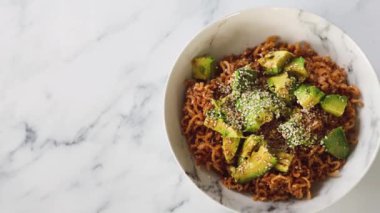 Avokado ve kızarmış soğanlı vejetaryen sarımsak ve zencefilli erişte, sağlıklı bitki temelli yemek tarifleri.