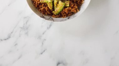 Avokado ve kızarmış soğanlı vejetaryen sarımsak ve zencefilli erişte, sağlıklı bitki temelli yemek tarifleri.