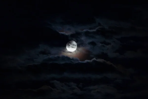 夜空に暗い雲を前に満月が望遠レンズで撮影され ロイヤリティフリーのストック写真