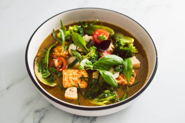 Kızarmış ipek tofu brokoliyle vegan Thai yeşil körisi ve bahçeden taze toplanmış bezelyeler, sağlıklı bitki temelli yemek tarifleri.