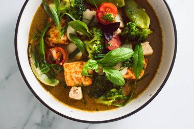 Kızarmış ipek tofu brokoliyle vegan Thai yeşil körisi ve bahçeden taze toplanmış bezelyeler, sağlıklı bitki temelli yemek tarifleri.