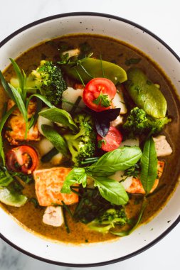 Kızarmış ipek tofu brokoliyle vegan Thai yeşil körisi ve bahçeden taze toplanmış bezelyeler, sağlıklı bitki temelli yemek tarifleri.