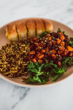 Vejetaryen kızartılmış balkabağı ve lahana cipsi salatası dilimlenmiş pesto tofu ve sarımsaklı ekmek sağlıklı bitki temelli yemek tarifleri.