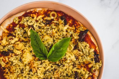 Sütsüz peynirli, kurutulmuş domatesli ve zeytinli vejetaryen pizza, sağlıklı bitki temelli yemek tarifleri.